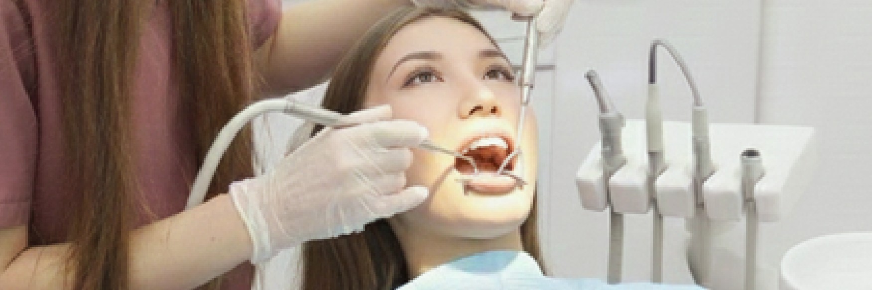 Dr. Shalev treating a patient in the dental chair, using a mirror and suction.